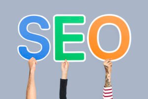 Hands holding up colorful letters forming the abbreviation SEO