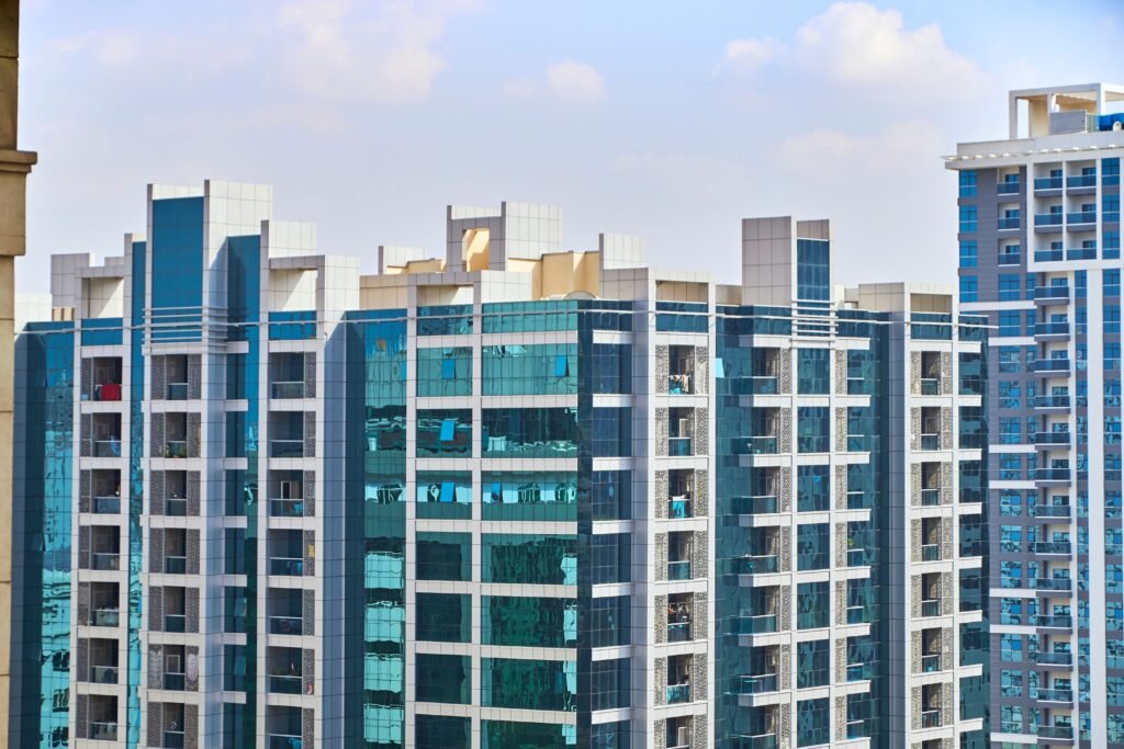 A cityscape view of modern high-rise buildings with reflective glass facades under a blue sky.